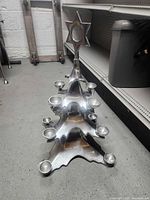 Front angled view of aluminum Christmas tree candle holder showing star finial and tea light cups