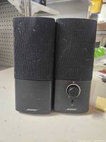 Front view of both Bose speakers showing grilles, volume knob and logos