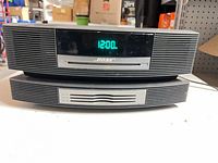 Front view of Bose Wave Music System stacked on Multi-CD Changer showing clock display and CD slot
