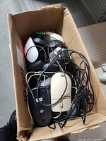 Top view of box containing several wired computer mice with cords