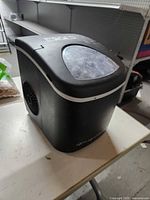 Front left view of Frigidaire black countertop ice maker on table