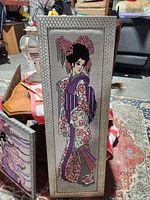 Tall vertical framed needlepoint of standing geisha