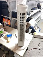 Full view of the Holmes white tower fan on table showing height, base, and grille
