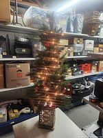 Full view of 49-inch pre-lit tabletop Christmas tree illuminated on shelving