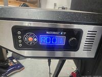 Digital control panel lit up with RO01 code on blue LED, Masterbuilt branding