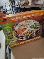 Front of product box showing Nostalgia Electric Lazy-Susan Buffet, picture of unit with food