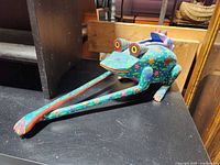 Side view of carved wood frog with vibrant patterns and smaller frog on back