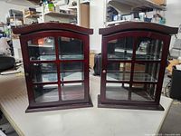 Front view of both matching wood and glass wall cabinets on table