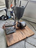 Full view of drill press frame mounted on plywood base with attached motor