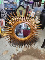 Front view of Uttermost sunburst mirror showing gold wood spikes and reflective glass