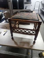 Overall view of oak footstool showing turned legs, lattice stretcher, tapestry seat