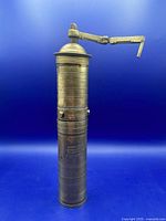 Full view of brass cylindrical grinder with crank attached