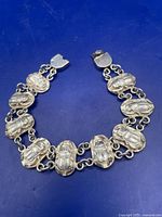 Full view of bracelet arranged in semi-circle showing nine scarab links and clasp