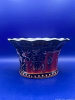 Front view of glazed porcelain jardiniere with painted figures and red panels