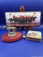 Group shot showing stone print on stand, pewter figurine, spoon, and coaster set