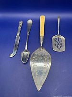 Four serving implements laid out side by side on blue background