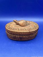 Full side view of oval rattan trinket box with carved turtle on flat lid