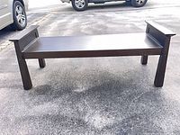 Full view of dark wood bench on driveway