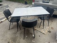 Table and three chairs grouped together outdoors