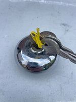 Top view showing chrome cap with key inserted and twist-tied spare key
