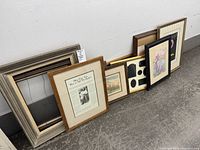 Group of assorted frames lined against wall