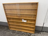 Front view of wooden display case showing shelves and one clear sliding panel