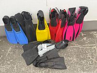 Eight pairs of assorted fins arranged against wall and floor