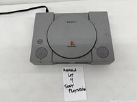 Top view of gray Nintendo console with closed lid and visible power cord