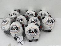 Group of ten identical Bing Dwen Dwen panda mascot plush toys in plastic wrap