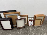 Group of all frames lined against wall showing range of sizes and finishes