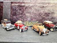 Group shot of four vintage model cars with Packard sign and Tucker plaque