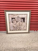 Full view of framed figural print against red backdrop