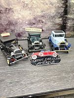 Front view of three Hubley Model A cars and plaque