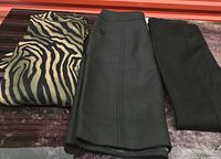 Folded zebra print sweater next to black skirt and black ponte pants