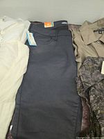 Four garments laid flat: white tops, navy pants, taupe/floral top