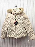 Front view of cream quilted puffer jacket hanging, shows full garment and condition