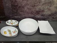 All four porcelain serving pieces arranged: covered dish with lid, oval bowl, round bowl, rectangular platter