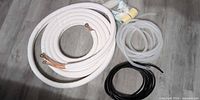 Full kit showing copper line set, drain hose, cable, tape and putty