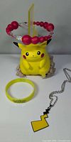 Pikachu vinyl figure, yellow wristband, pendant necklace
