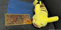 Pikachu plush beside gold foil note in sleeve
