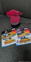 Grogu LED lamp lit red beside two sealed Hot Wheels RacerVerse packages