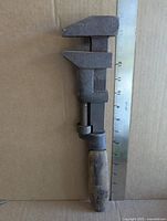 Full view of monkey wrench beside ruler