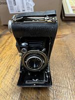 Front view of Kodak Vigilant camera open showing lens, bellows, shutter markings