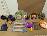 Group shot of several figures and accessories including Phil figures, column rollers, purple trumpet, Zeus head ball, rock bases and sealed bagged toy