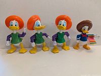Five PVC duck figures; four Donald Duck in orange sombreros and green tunics, one additional Donald in blue jacket with brown sombrero and multicolour serape