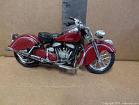 Right side view of red Maisto Indian Chief motorcycle model against ruler showing length