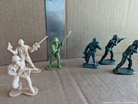 Mixed tan, green and grey toy soldiers standing next to ruler for scale
