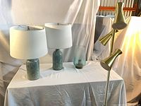 Group shot showing two teal ceramic table lamps with white shades, blue glass vase, brass triple-head floor lamp
