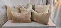Five beige and cream throw pillows front view
