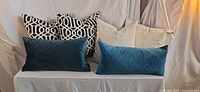 All seven pillows arranged on bench, showing front and back rows